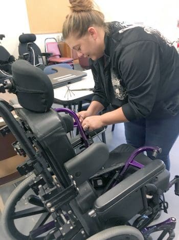 A woman leans over a wheelchair in a room full of DME
