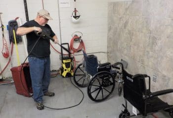 A man spraying a manual wheelchair.