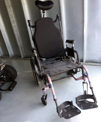 Manual wheelchair with stars and stripes legs and missing seat cushion.