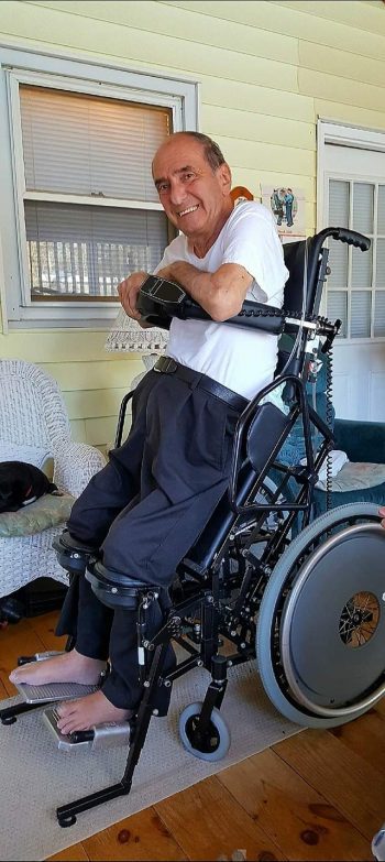 Man smiling upright in a standing wheelchair.