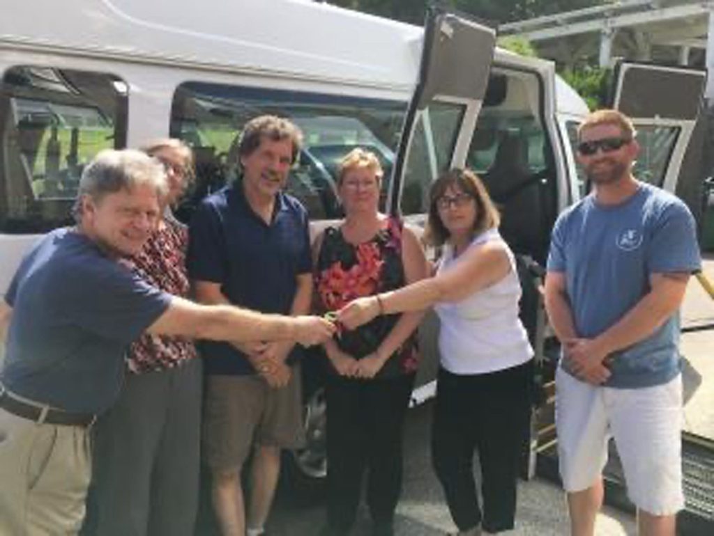 Group of people in front of a new van.