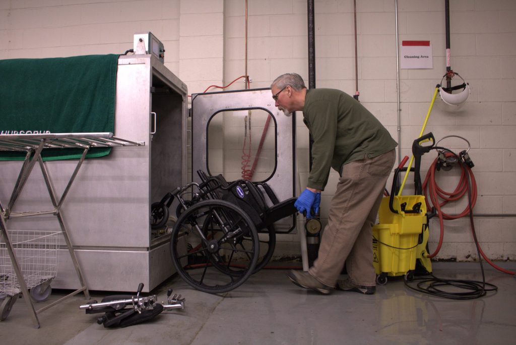 staff member placing wheelchair into Hubscrub machine