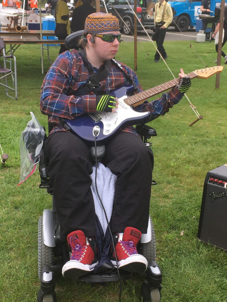 Person in motorized wheelchair playing a guitar.