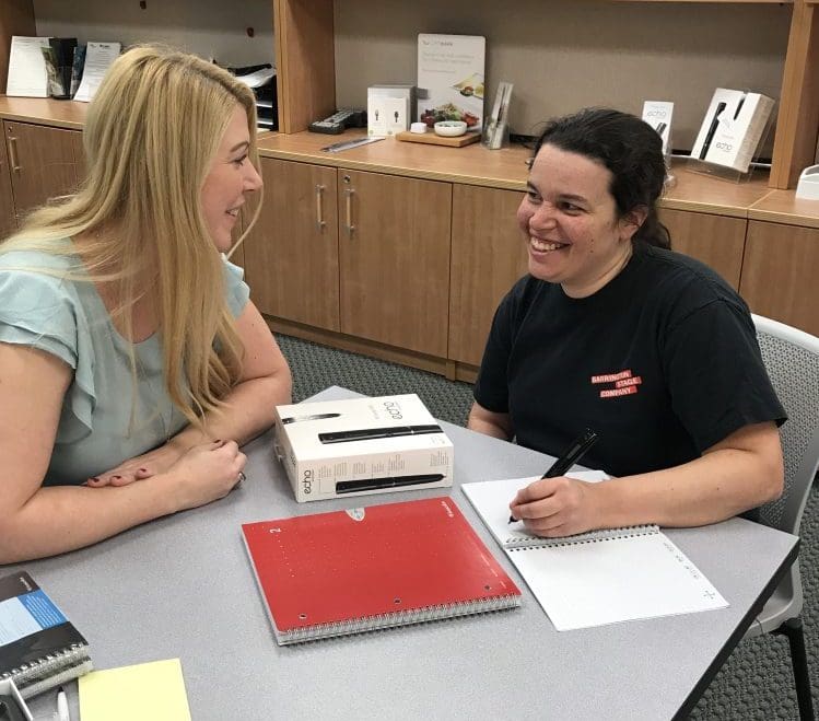 two women smiling looking at each other at an office table