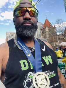 A bearded man wearing sunglasses and a medal looking off into the distance.